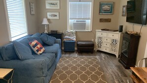 A living room with a blue sofa, a patterned rug, a wooden cabinet, and a television. - Coastal Charm!!!! Super cute and clean!! (Port St Joe)