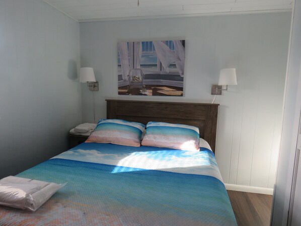 Un dormitorio con cama, mesitas de noche y un cuadro en la pared.