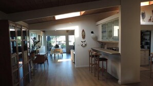 A spacious kitchen with wooden flooring, a dining area with chairs, and a bar area with stools. - Beautiful Ocean View Home Overlooking San Diego Perfect For Your Family Vacation (San Diego)