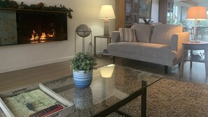 A living room with a fireplace, a sofa, a coffee table, and a lamp. - Beautiful Ocean View Home Overlooking San Diego Perfect For Your Family Vacation (San Diego)