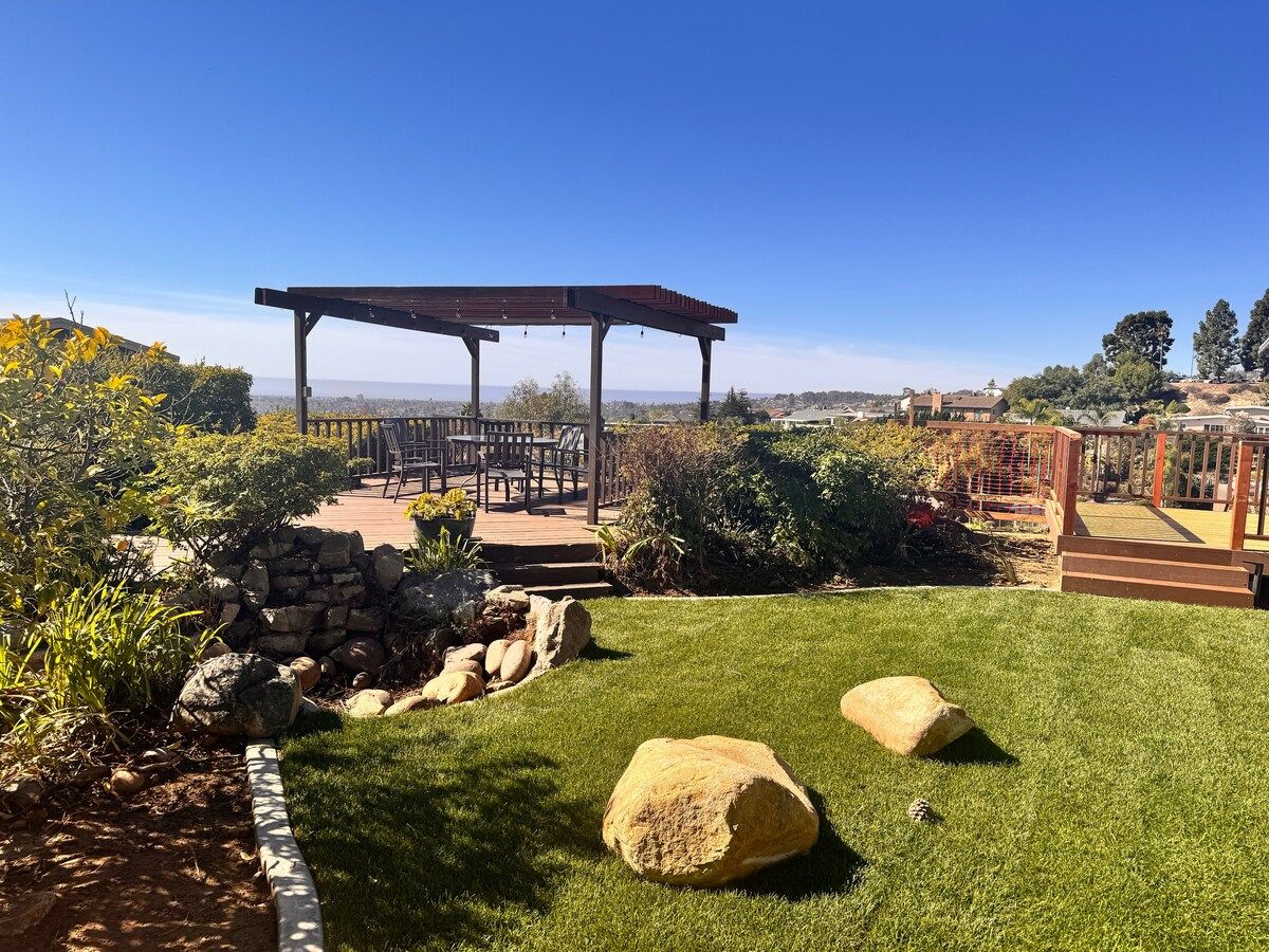 A garden with a pergola, seating area, and a view of the city.