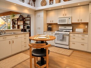 A modern kitchen with a round dining table, built-in cabinets, a microwave, stove, and a coffee maker.