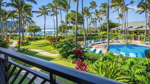 A resort with a pool, palm trees, and a view of the ocean.