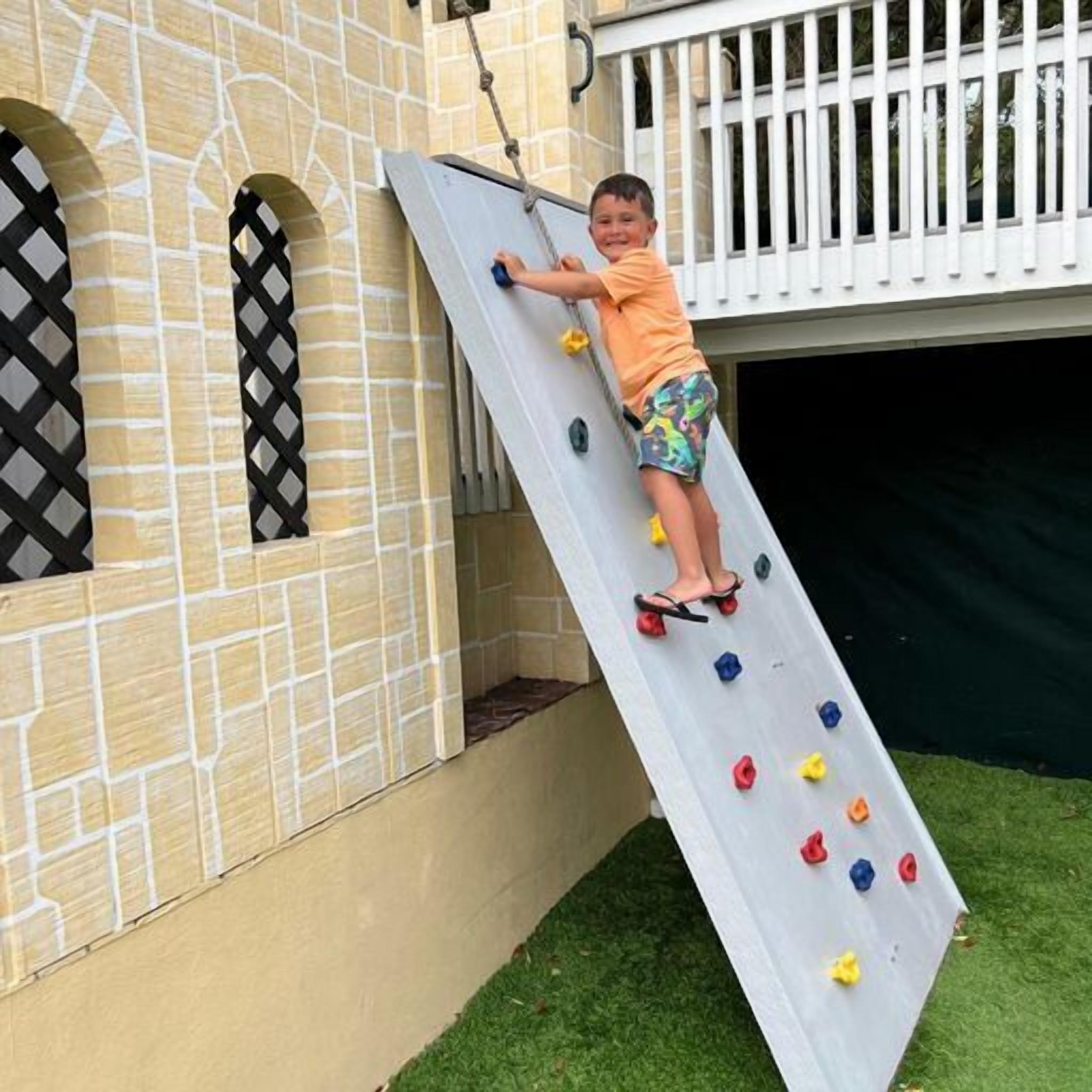 A child climbing a climbing wall with colorful holds.