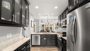 Una cocina moderna con un refrigerador de acero inoxidable, gabinetes negros y una encimera de mármol.