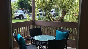 A covered patio with a round glass table and four chairs, surrounded by a wooden railing. - Adorable Studio, sleeps 3 - Totally renovated in 2018 (Princeville)