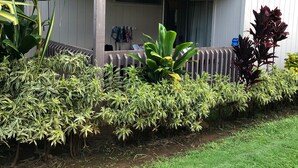 A two-story building with a balcony, surrounded by various plants and a well-maintained lawn. - Adorable Studio, sleeps 3 - Totally renovated in 2018 (Princeville)