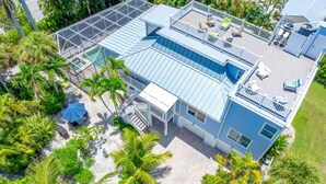 A large house with a spacious deck, multiple windows, and a swimming pool. - Beautiful 5 Bedroom Captiva Pool Home Central to Stunning Beaches (Captiva)