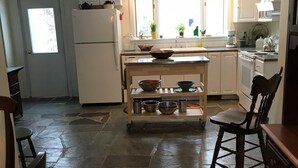 Uma cozinha com piso de pedra, mesa de madeira e um letreiro que diz "GATHER".