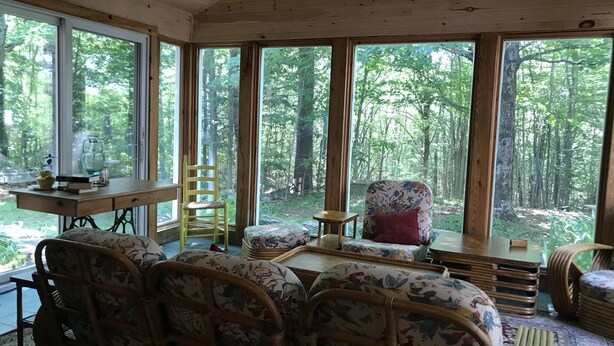 Um quarto aconchegante com janelas amplas, móveis de vime e vista para uma floresta.