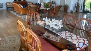 Amplia sala de estar con una gran mesa de comedor, múltiples sillas, ventiladores de techo y un televisor.