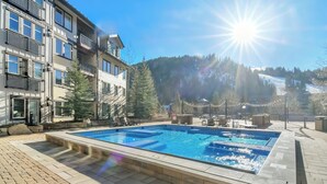 Une piscine avec vue sur une montagne et un immeuble à plusieurs étages.