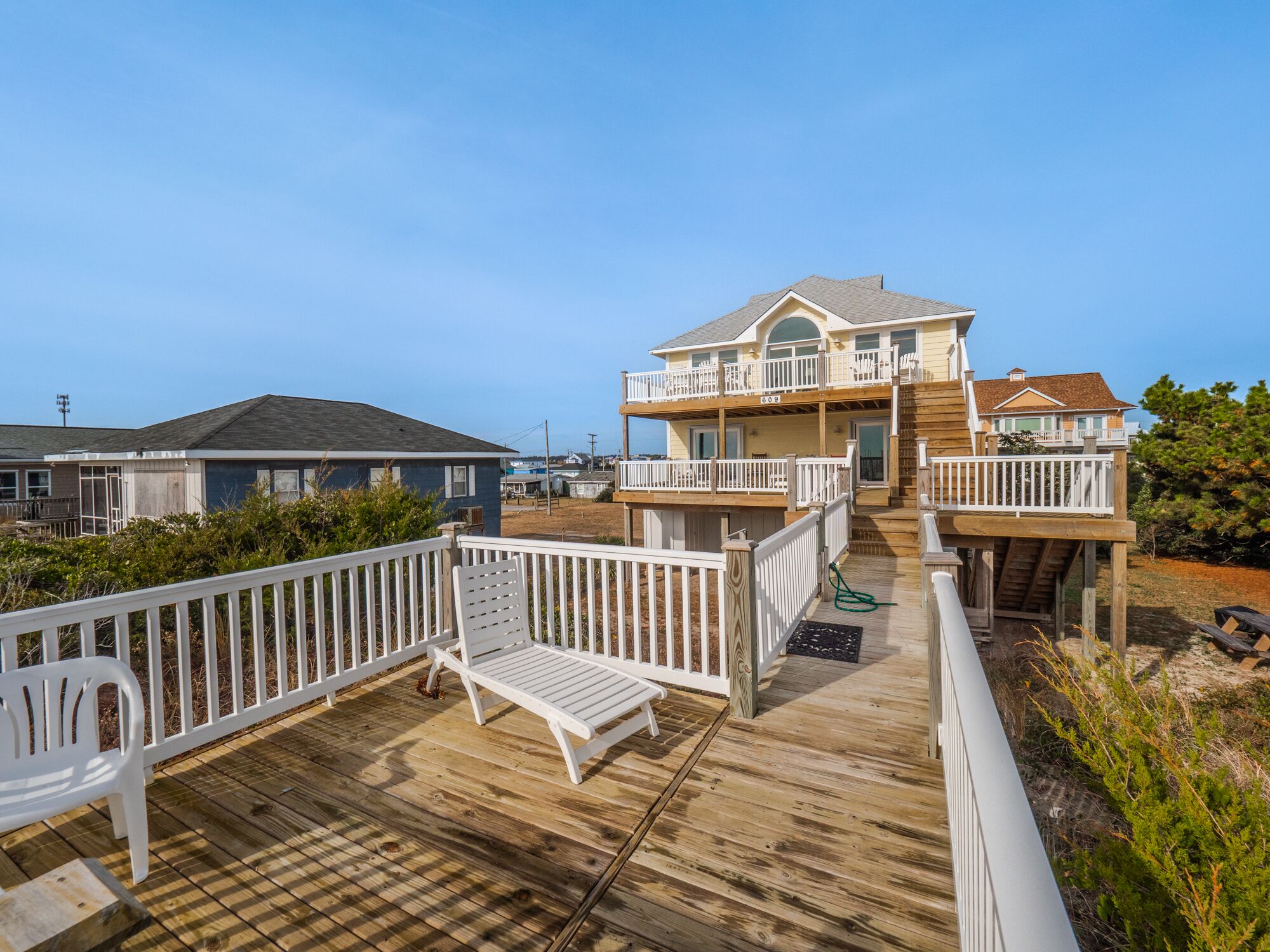 A two-story house with a wooden deck and white railings.