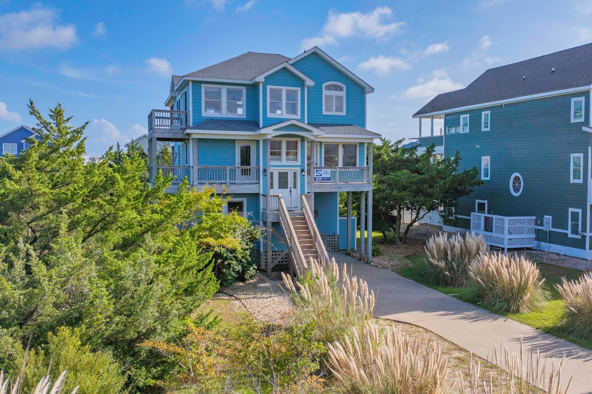 A two-story house with a balcony, a front porch, and a staircase leading to the second floor.