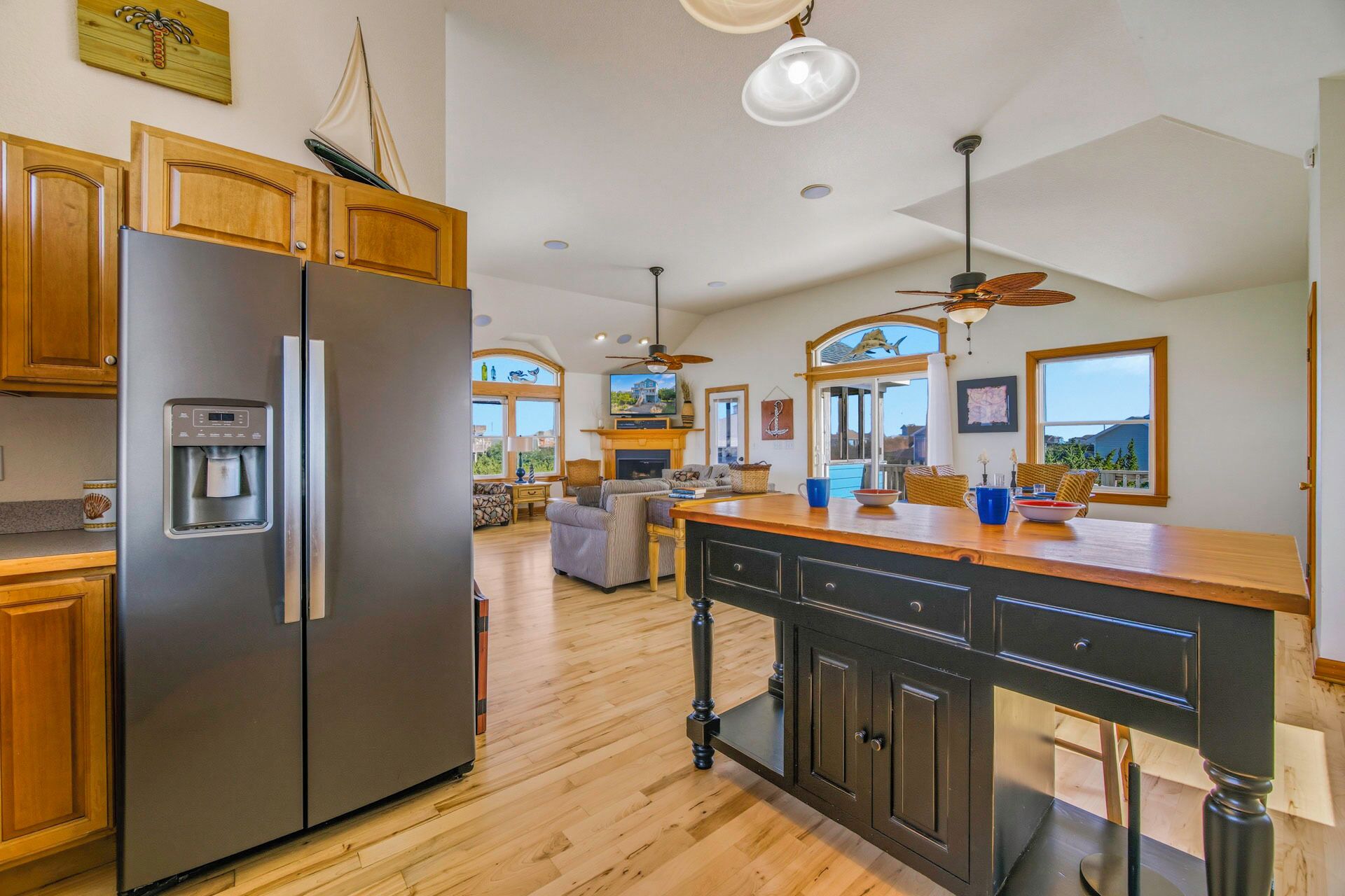 A spacious kitchen with wooden cabinets, a stainless steel refrigerator, a water dispenser, and a dining area with a wooden table and chairs.