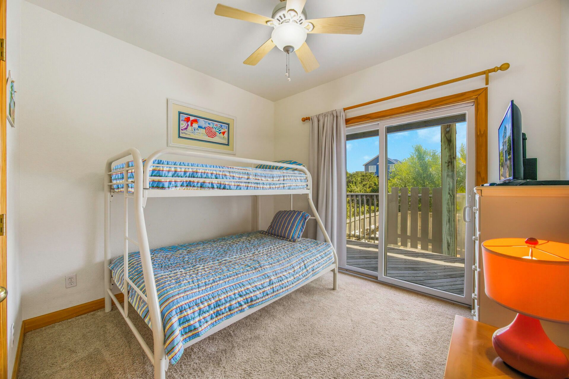 A bunk bed room with a ceiling fan, a window with curtains, and a view of the outside.