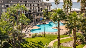 Un resort con piscina, palme e vista sull'oceano.