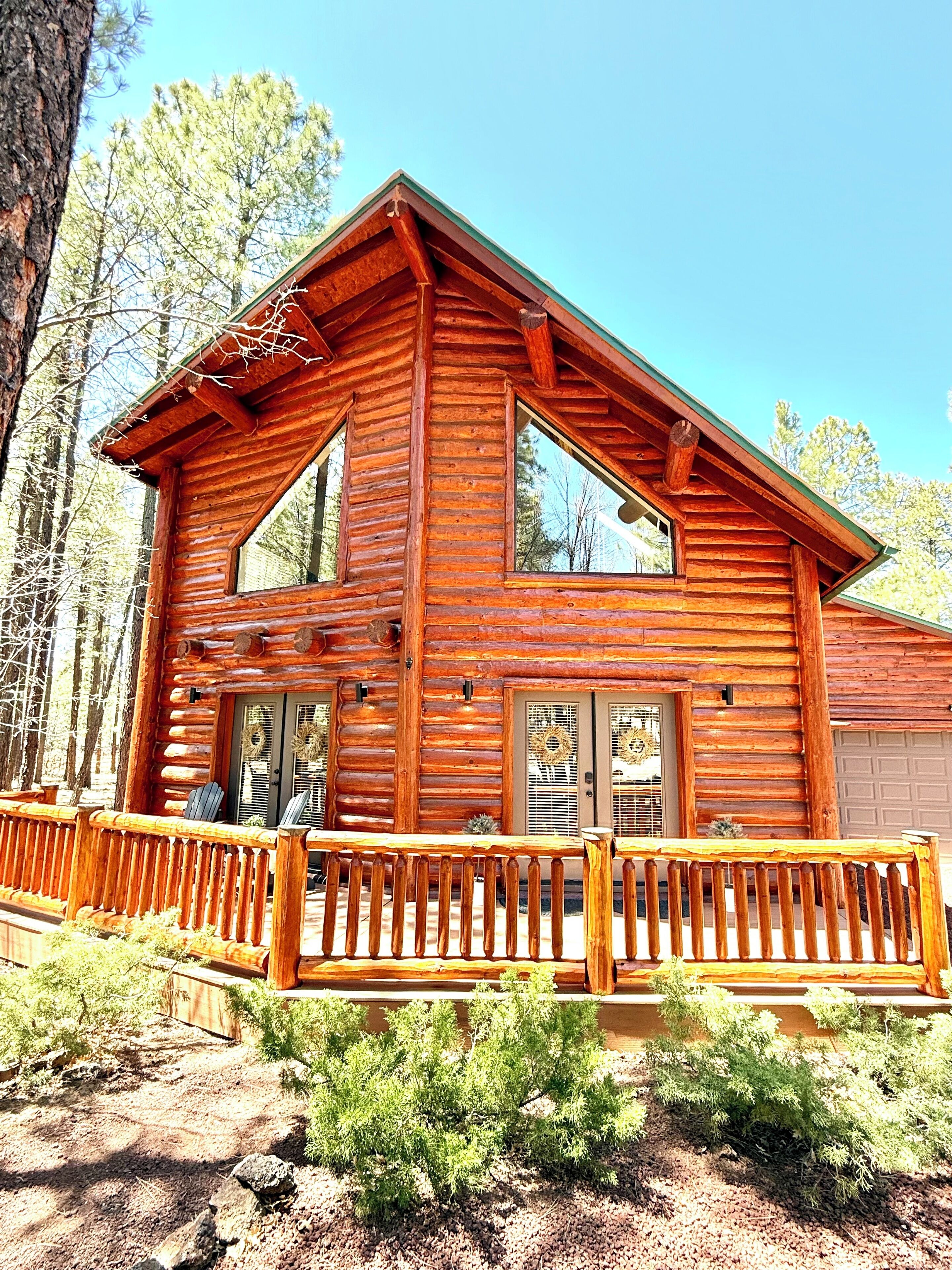 A log cabin with a wooden deck and a garage.