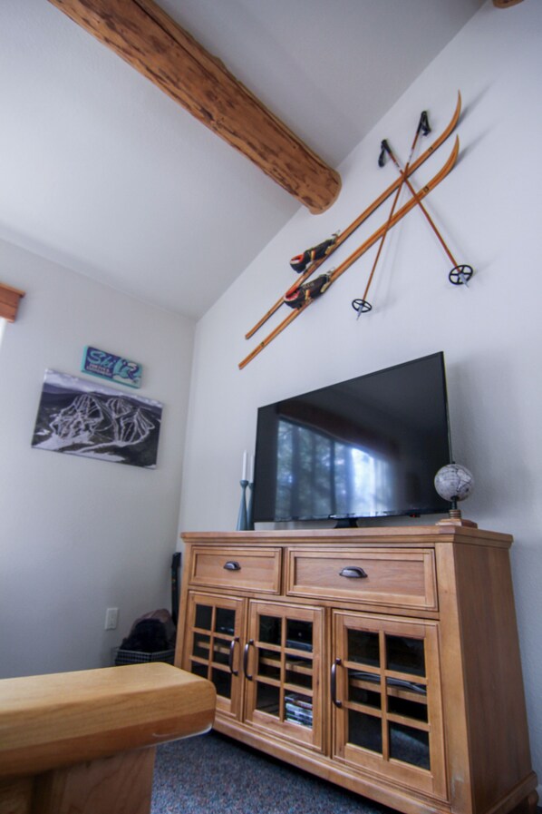 A room with a wooden cabinet, a television, and skis mounted on the wall.