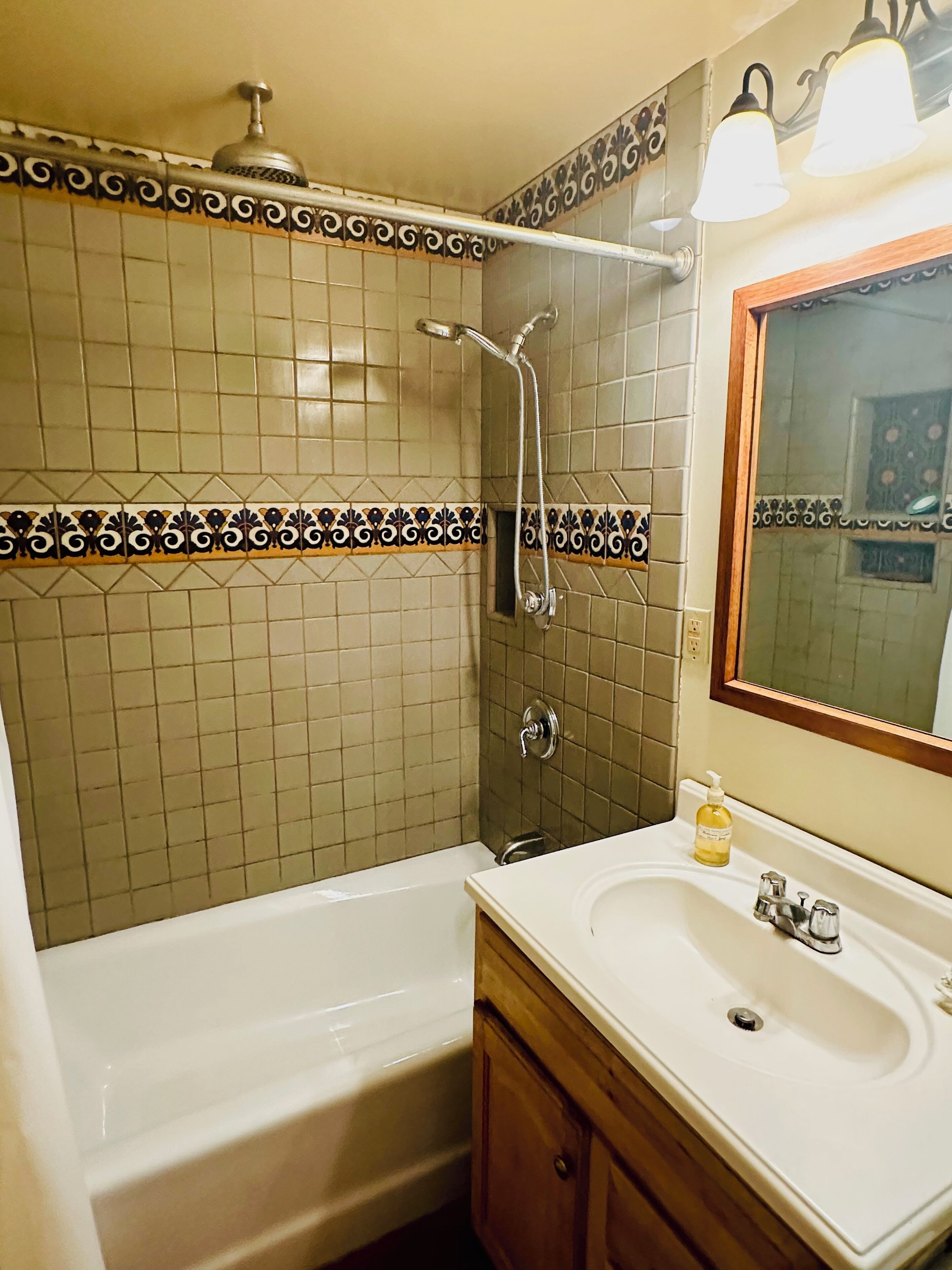 A bathroom with a bathtub, a shower, a sink, and a mirror.
