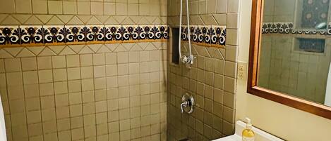 A bathroom with a bathtub, a shower, a sink, and a mirror.