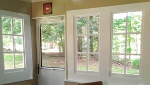 Una stanza con soffitto verde, un tavolo con tovaglia a motivi floreali, due sedie di legno e una porta con un piccolo quadro sopra.