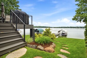 Imóvel à beira-mar com área externa coberta, degraus que levam a um deck e um cais com barco.