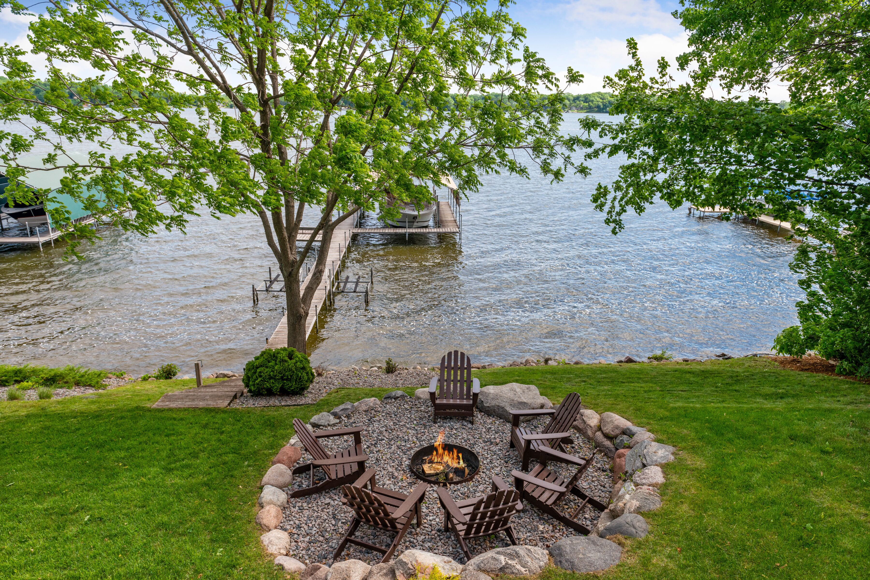 Gather around your private fire pit with lake views. Adirondack chairs circle the flames while your dock awaits peaceful evenings by the water.