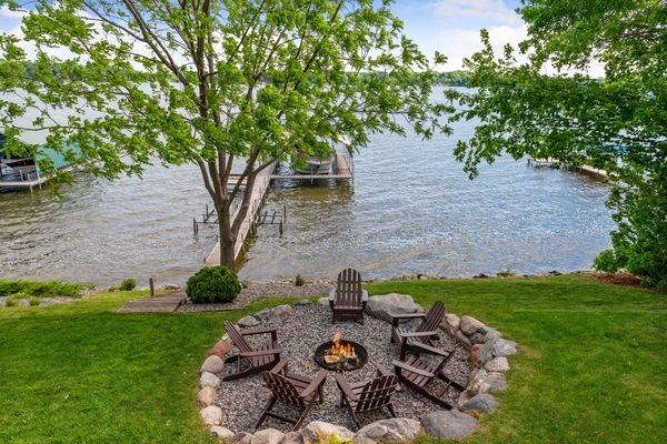 Gather around your private fire pit with lake views. Adirondack chairs circle the flames while your dock awaits peaceful evenings by the water.