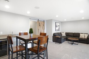 A modern living room with a dining table, chairs, a sofa, and a coffee table.