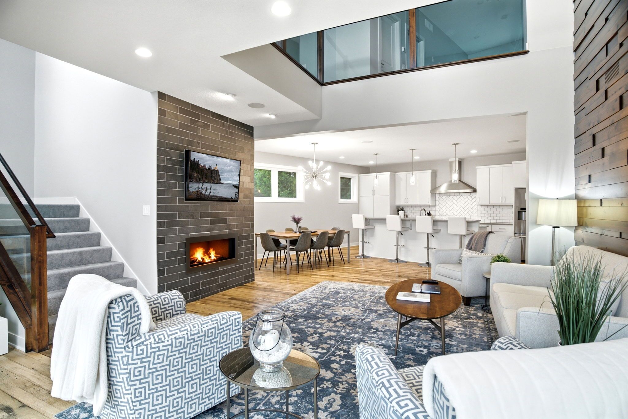 A modern living room with a fireplace, a dining area, and a kitchen.