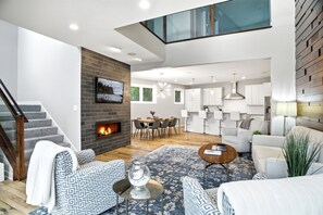 Uma sala de estar moderna com lareira, área de jantar e cozinha.