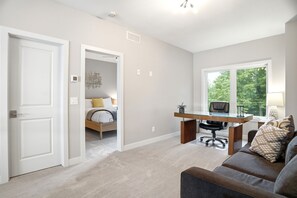 Un dormitorio moderno con cama, escritorio y ventana.