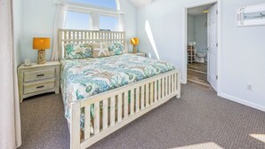 Ein Schlafzimmer mit einem Bett, zwei Nachttischen, einem Fenster und einer Tür zu einem anderen Raum.