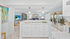 A spacious kitchen with a large island, pendant lighting, and a view to a balcony.