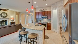 Una cocina moderna con encimeras de granito, electrodomésticos de acero inoxidable y una isla central con taburetes de bar.