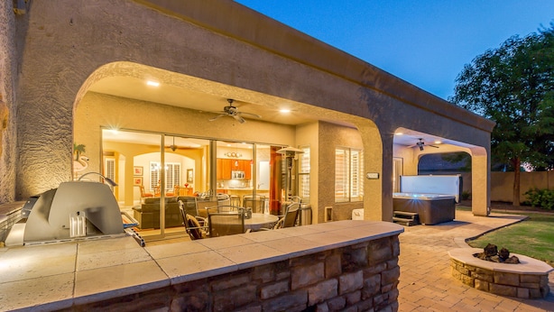 Un patio al aire libre con un muro de piedra, una parrilla y un jacuzzi.