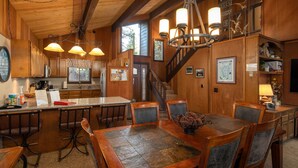 A wooden interior with a kitchen, dining area, and staircase. - Grainger by Hauserman Rental Group (Tahoe City)