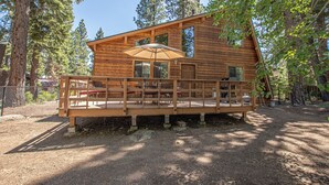 A wooden cabin with a deck, surrounded by trees. - Grainger by Hauserman Rental Group (Tahoe City)