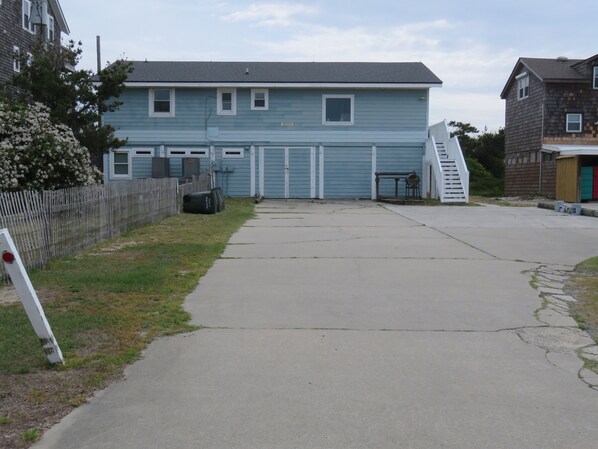 A two-story building with a garage door, a small porch, and a staircase leading to the garage.