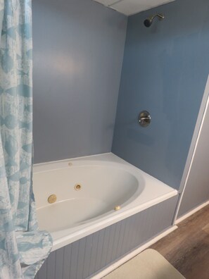 A bathroom with a white bathtub, a shower, and a blue wall.