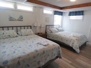 A room with two beds, each with a matching headboard and footboard, and a nightstand with a lamp between them.