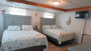 A hotel room with two beds, wooden floors, a flat-screen TV, and a wooden ceiling beam. - LastMinuteSpecial/OceanFront/Pool/HotTub/XBOXoneS/ping pong table (Nags Head)