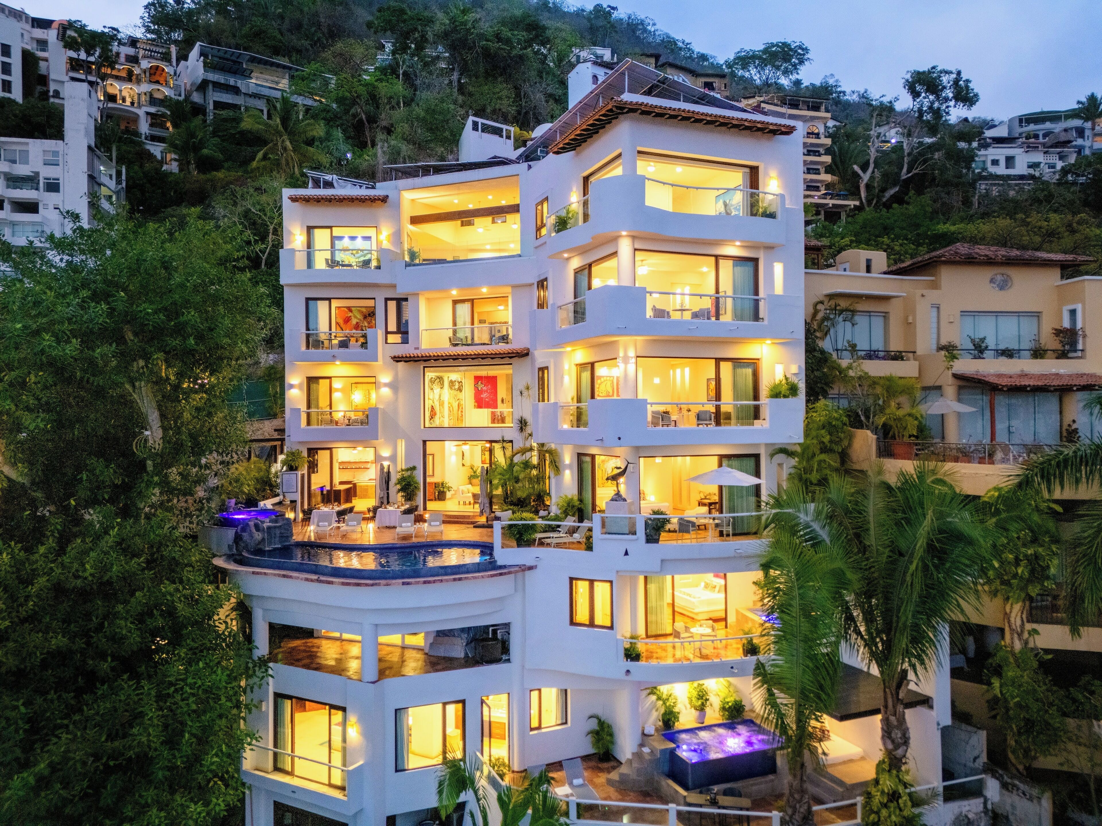 A multi-story hotel with balconies, a pool, and lush greenery.