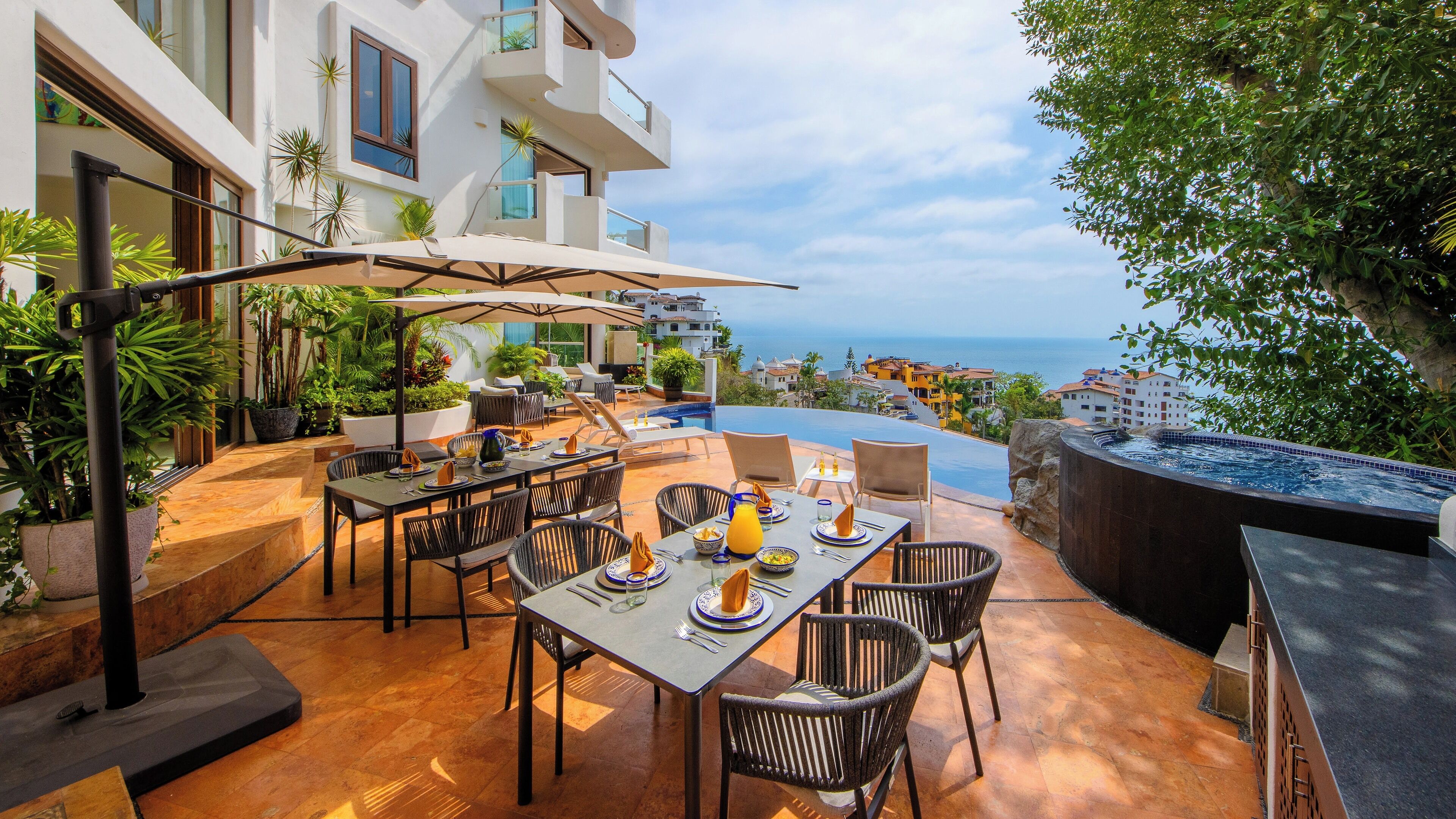 An outdoor dining area with a pool, overlooking a coastal view.