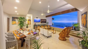A dining area with a view of the ocean, a bar, and artwork on the walls. - Villa Divina Luxury Boutique – Adults Only (Puerto Vallarta)