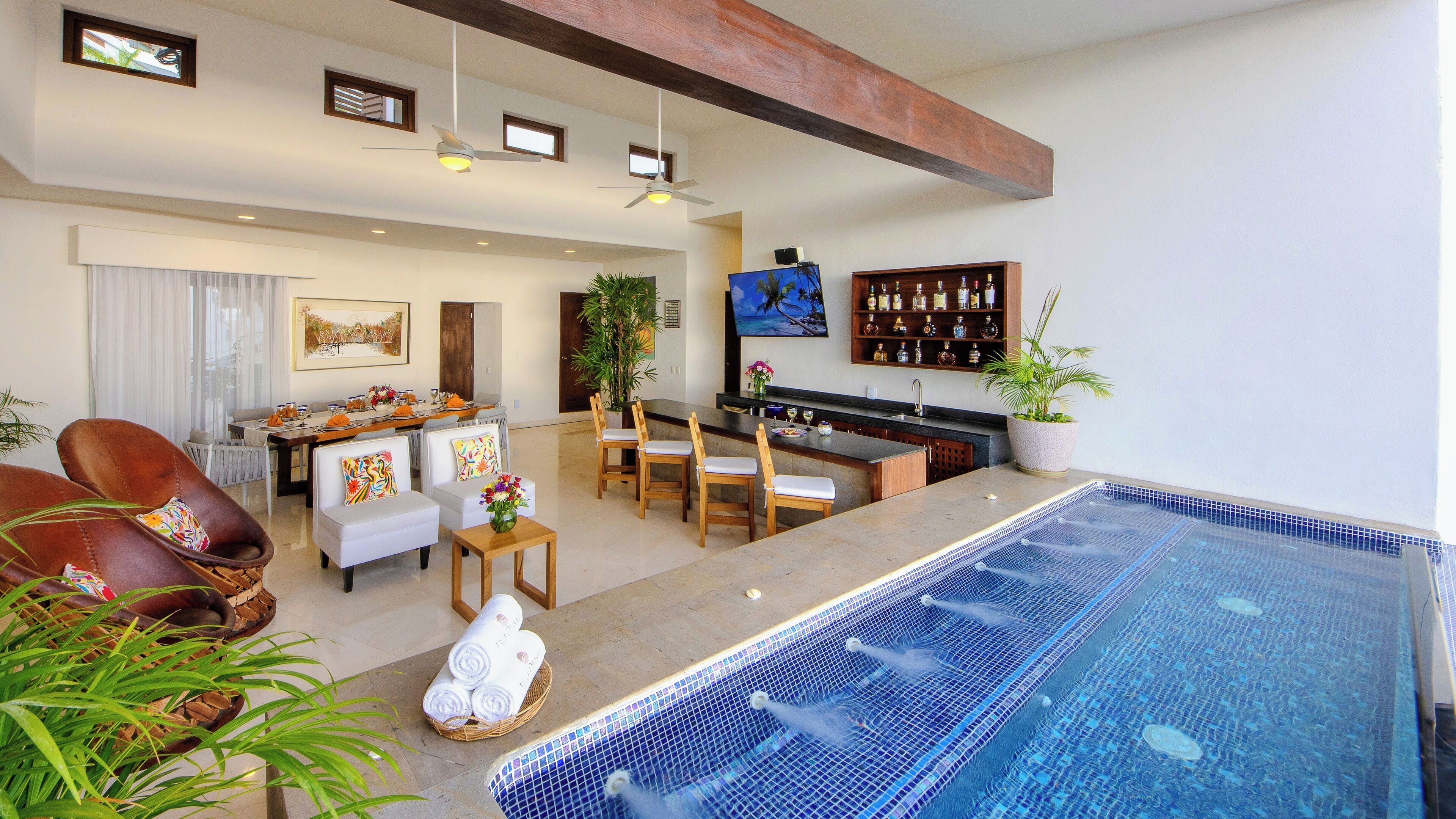 A spacious living area with a pool, a dining setup, and a bar area.