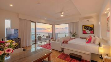 Una habitación de hotel moderna con balcón, cama, televisor y zona de comedor.