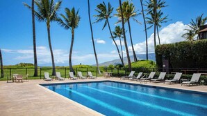 A swimming pool with lounge chairs and palm trees.