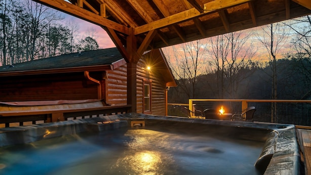 Un espace avec un bain à remous, une terrasse en bois et une vue sur la forêt environnante.